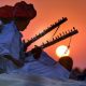 Two Folk Singers Playing Their Instruments In A Beautiful Sunset Background.