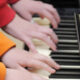 Children playing the piano with their hands