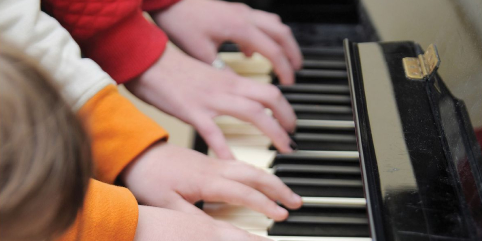 Children playing the piano with their hands